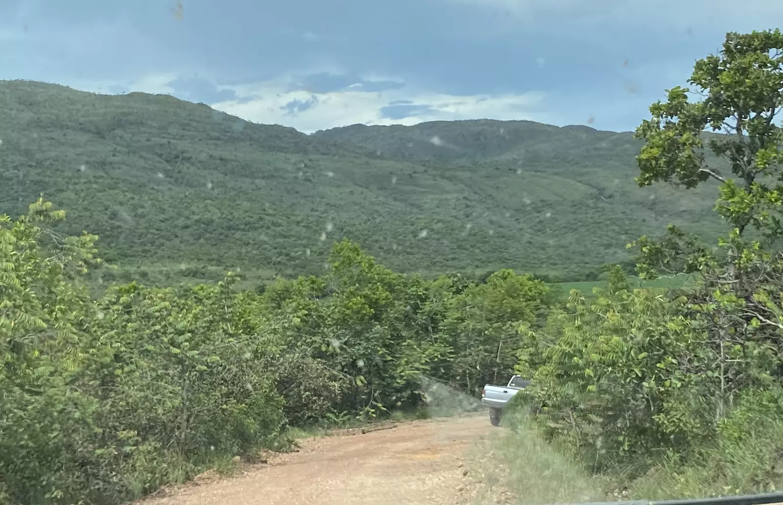 Estrada de terra vista de dentro da caminhonete, com a serra ao fundo